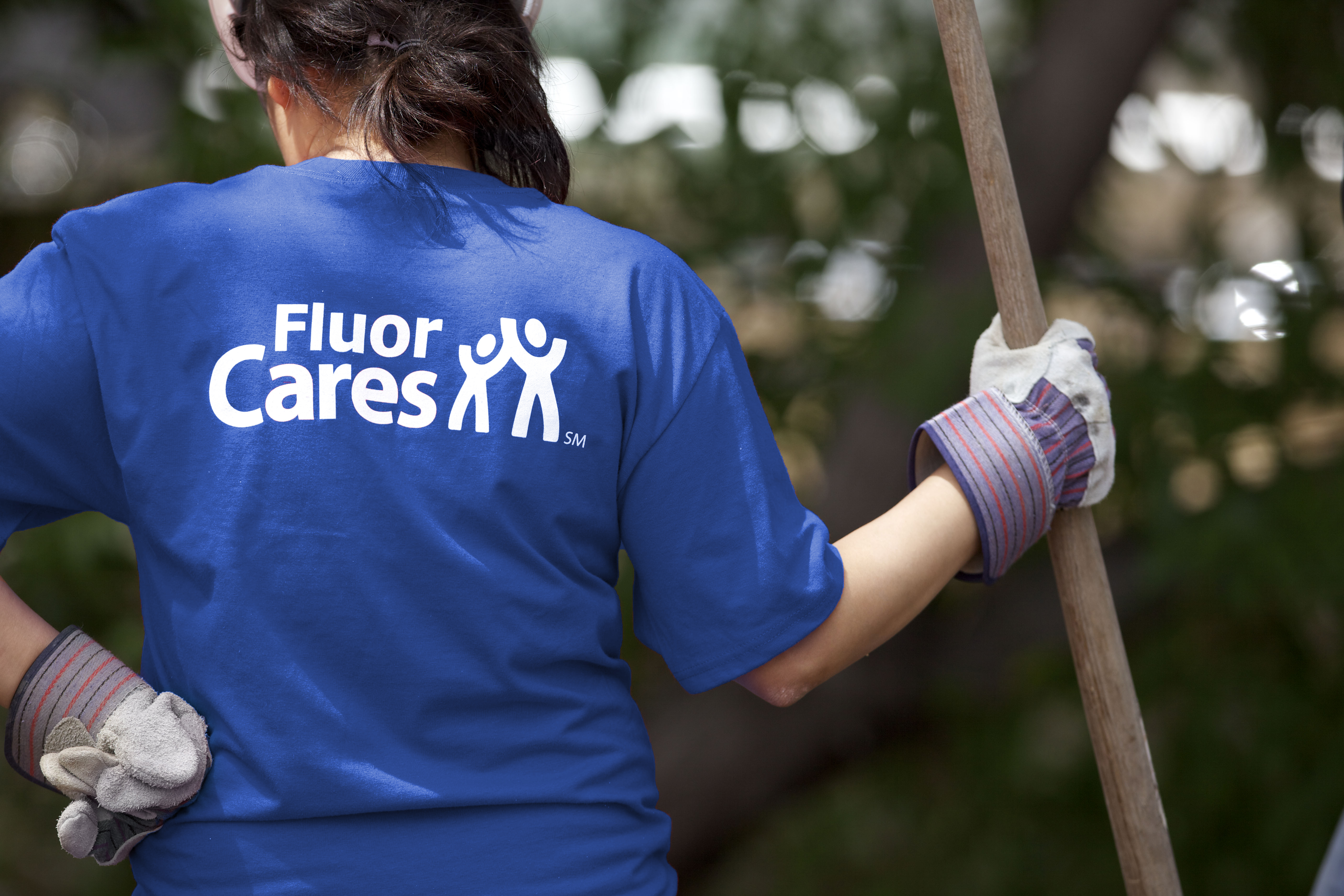 Woman with blue Fluor Cares t-shirt and landscaping tool